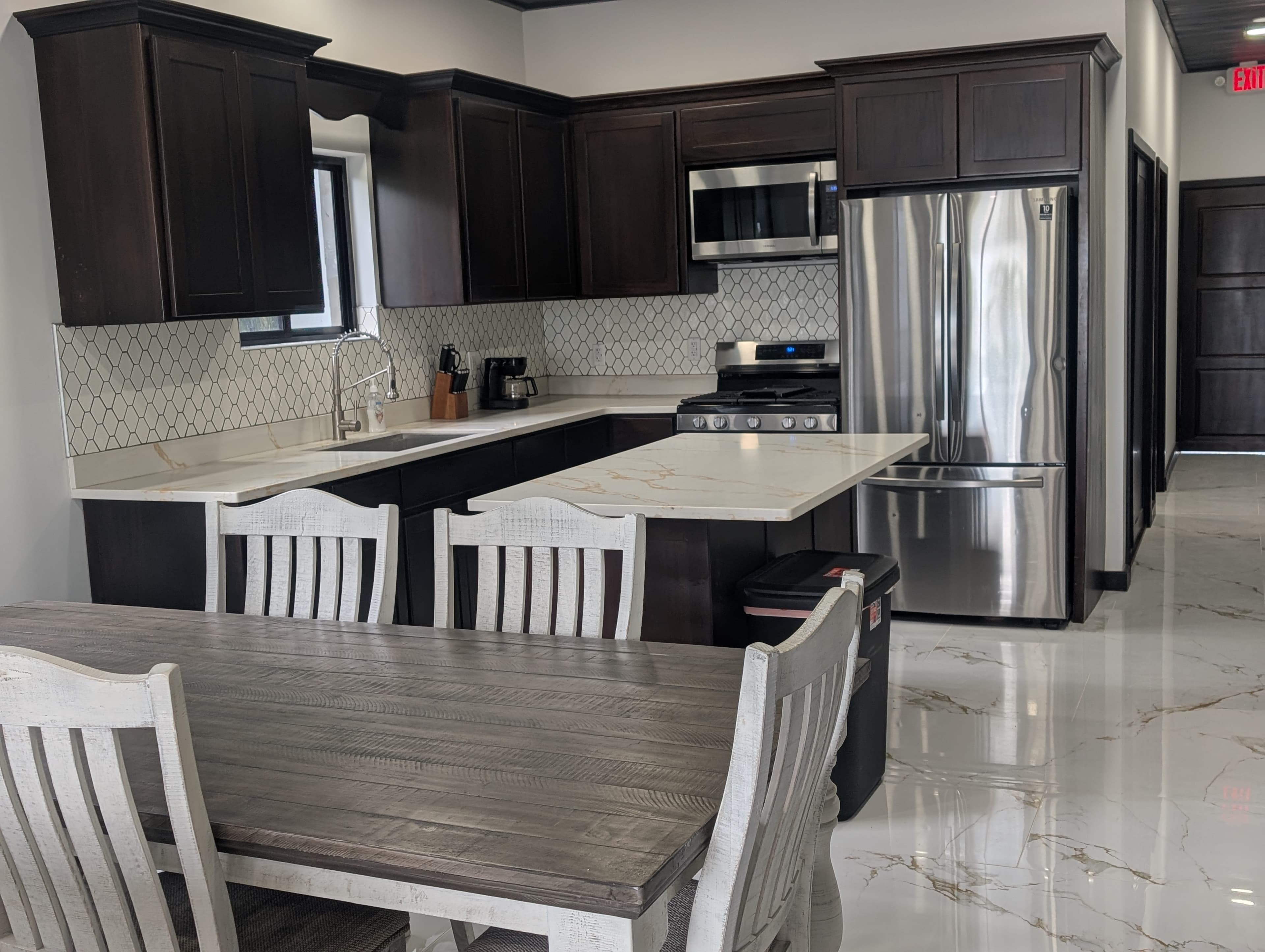 Modern kitchen, stainless steel appliances, island and 6 person table. expresso colored woodwork