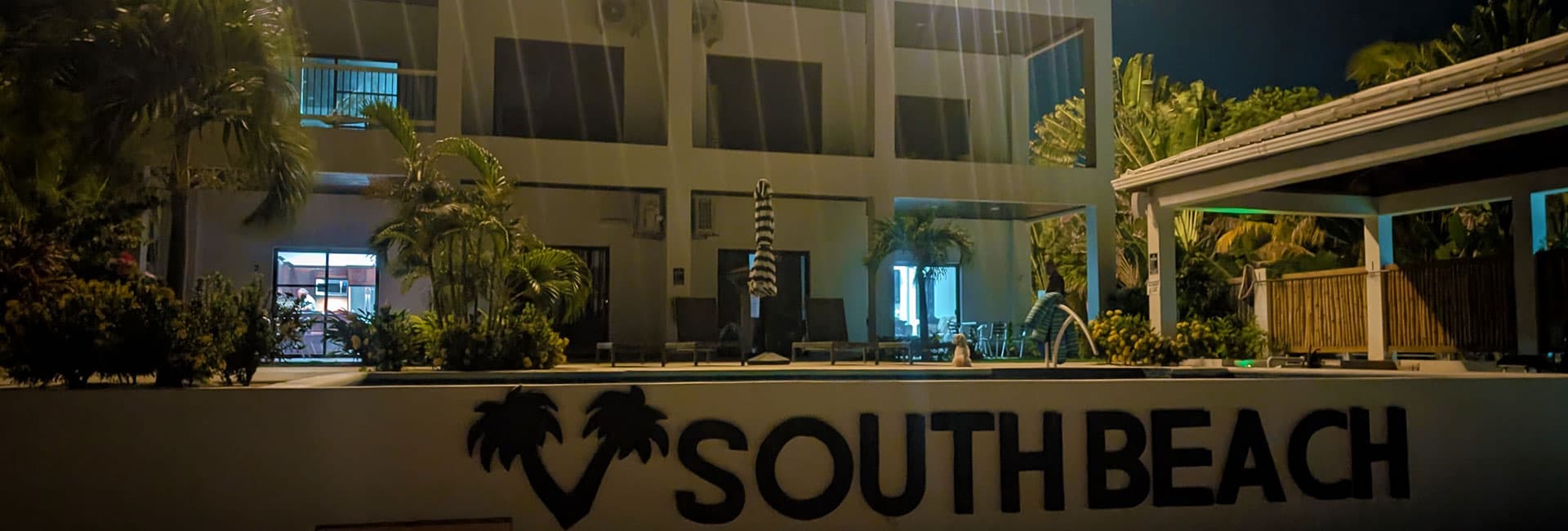 A nighttime view of the South Beach hotel, featuring palm trees and outdoor seating around a pool.