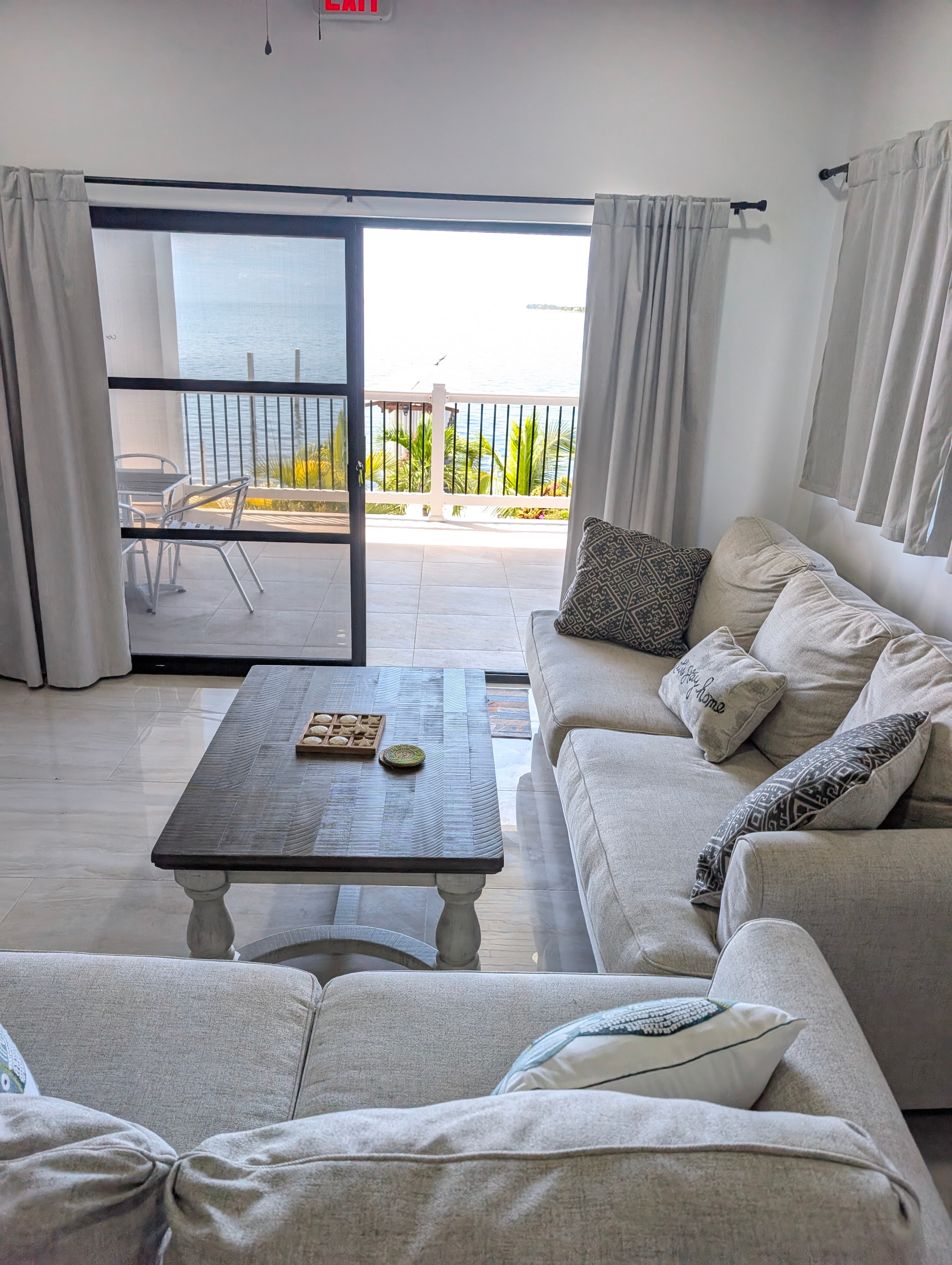 A cozy living room with a white sofa and a view of the ocean through large glass doors.