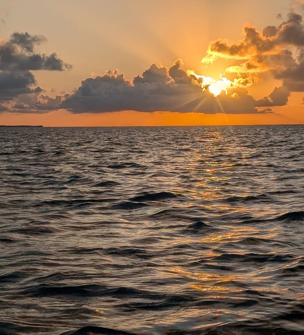 A stunning sunset over serene ocean waves, with vibrant colors and rays of sunlight peeking through clouds.