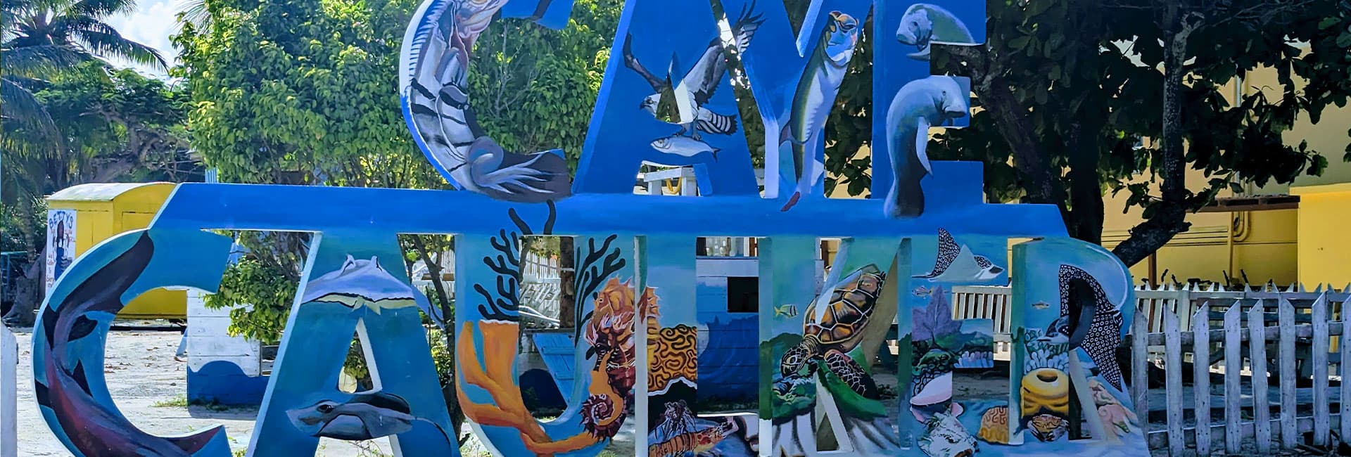 A colorful sign reading "Caye Caulker," adorned with marine-themed artwork.
