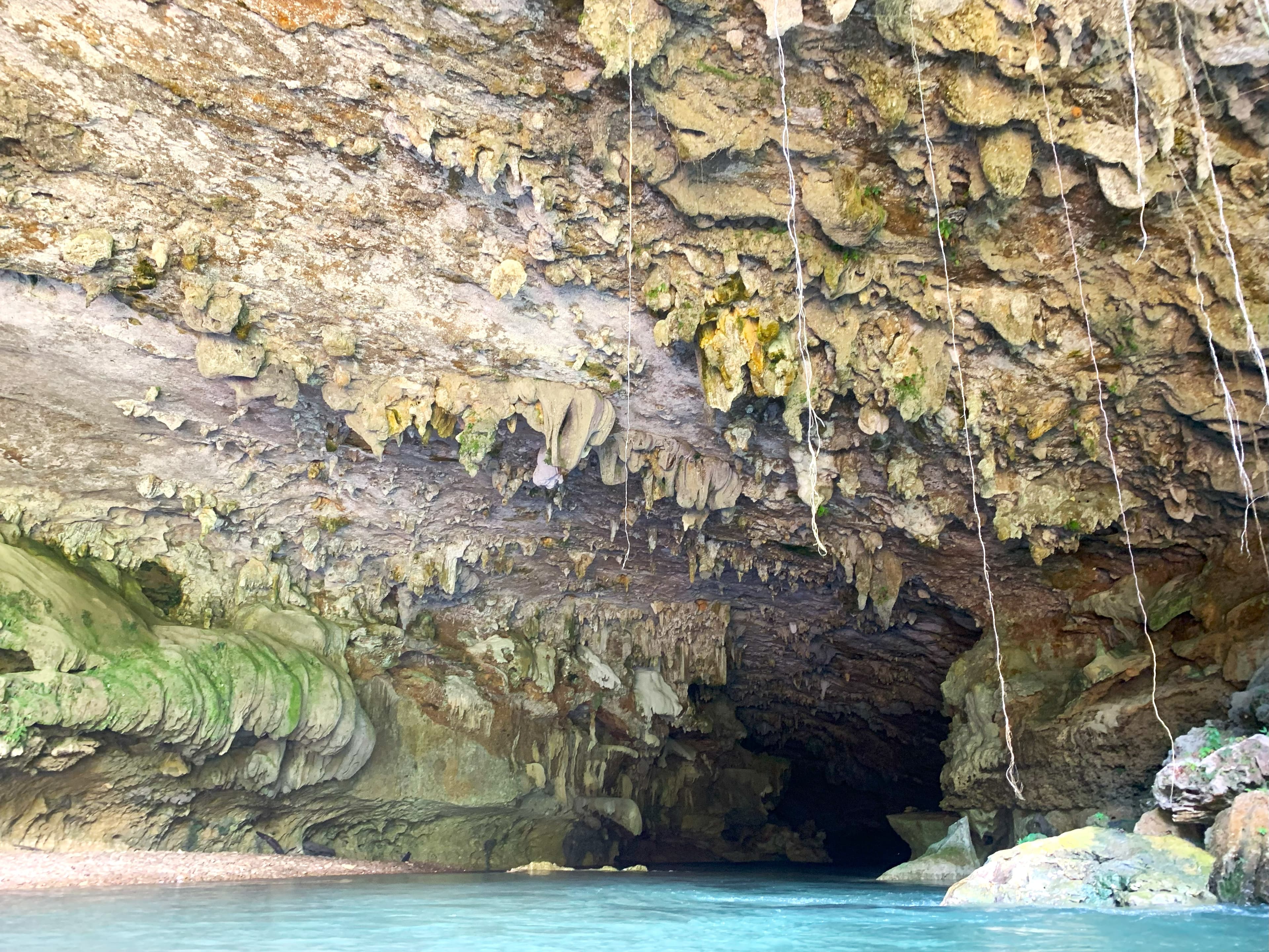 A dark cave with textured stone formations illuminated by water reflections.