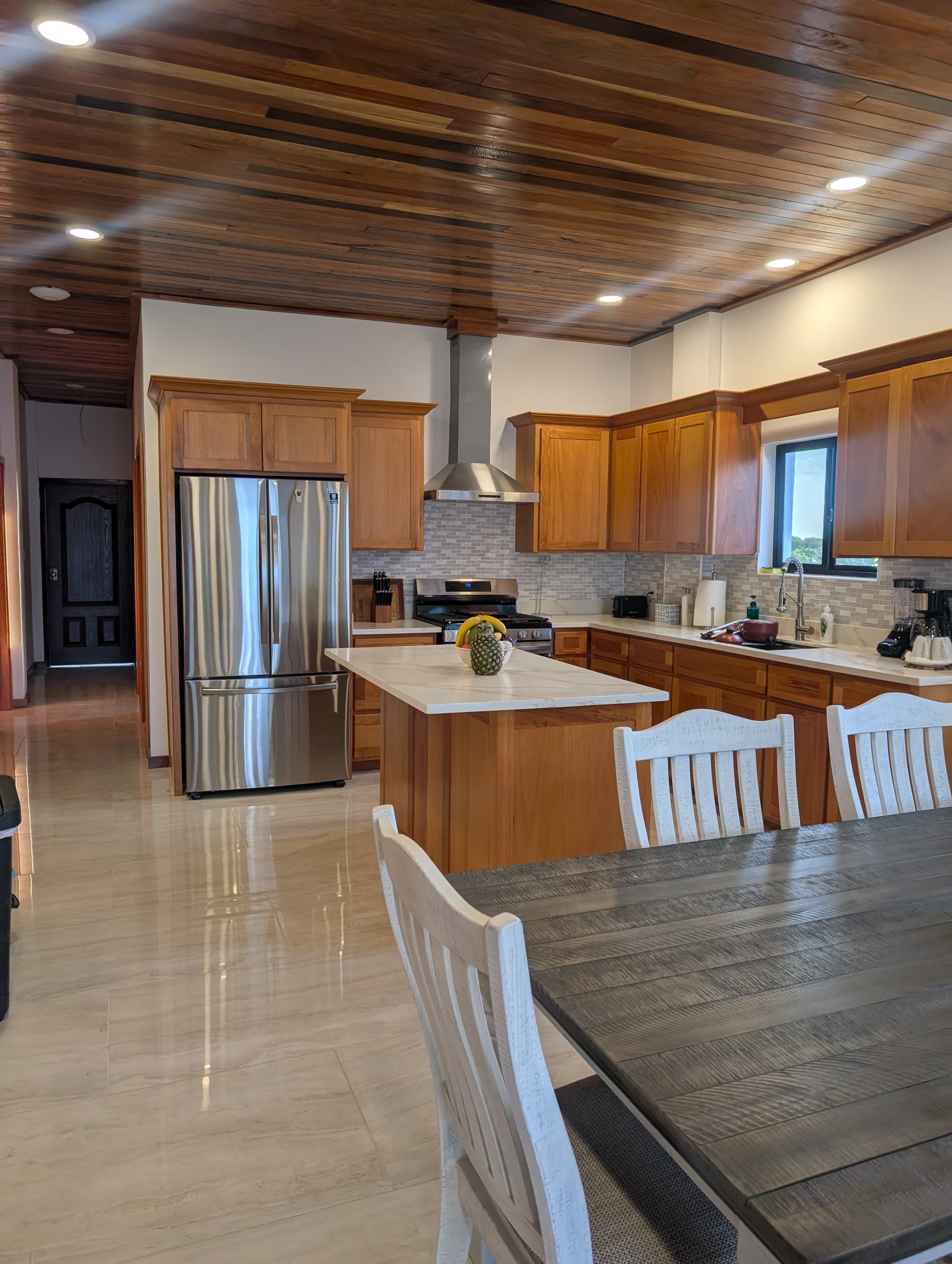 Modern kitchen featuring wooden cabinets, a stainless steel fridge, and a dining table.