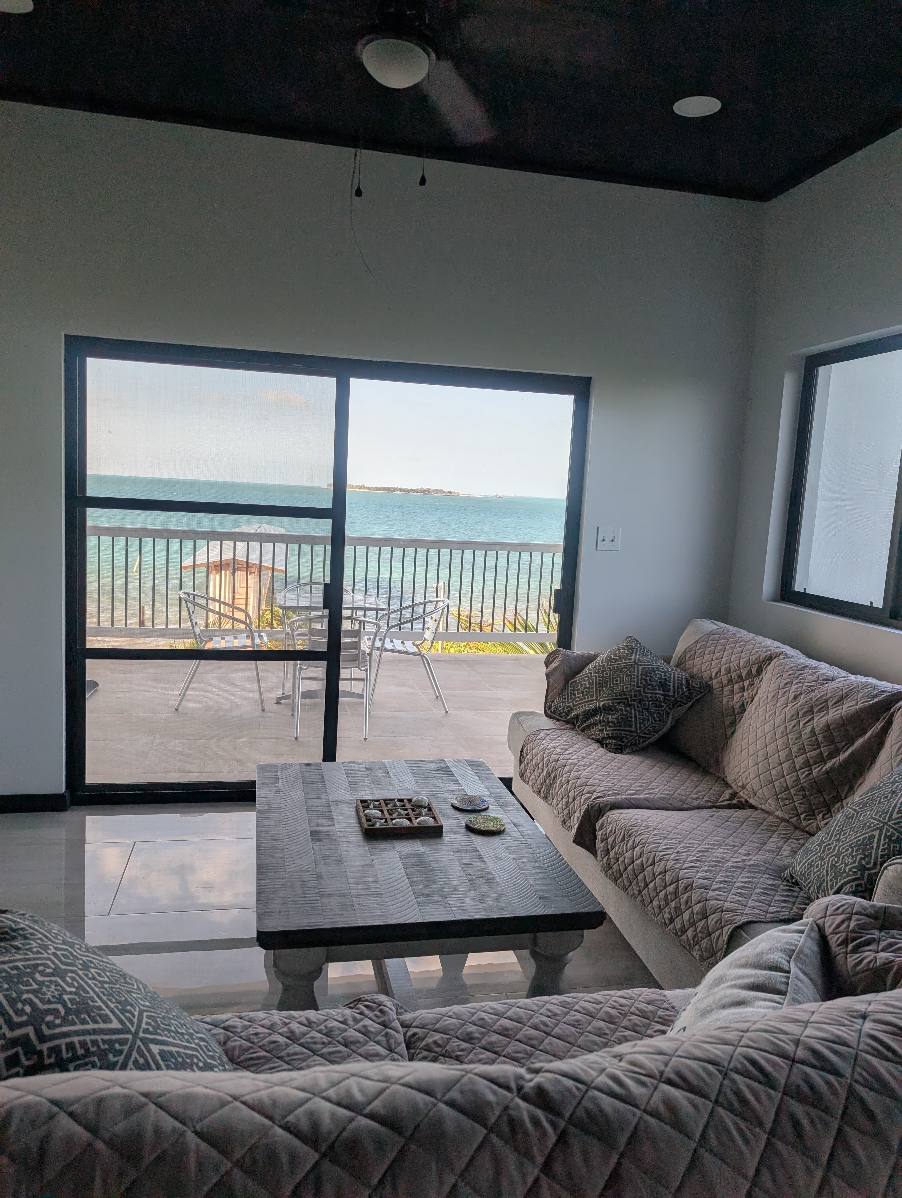 A cozy living room with a view of the ocean through a large screened window.