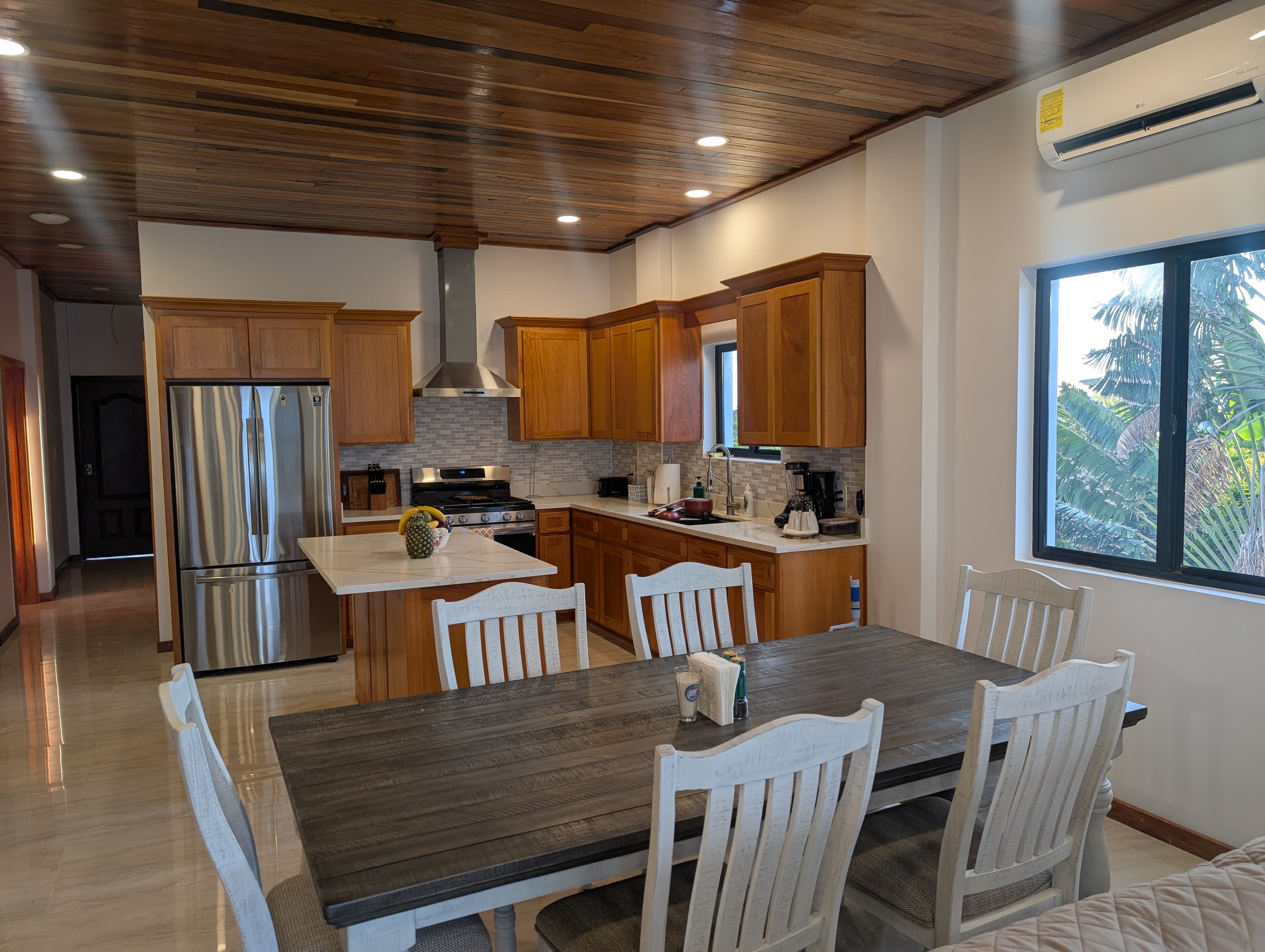 Modern kitchen with wooden cabinets, stainless steel appliances, and a dining table.
